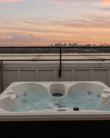 Hot tub on rooftop terrace with city skyline and frozen river at sunset